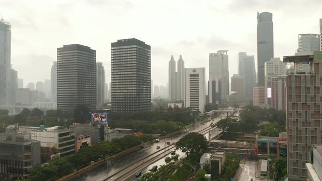 Aerial dolly shot flying across a multi lane road into the city on a wet rainy day in Jakarta, Indonesia