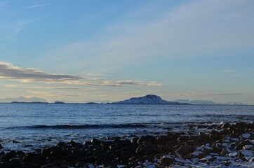 snowy sea shore with deep blue sea and sky at sunset