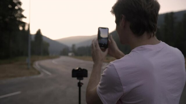 Person taking photo of highway at sunset in the Idaho forrest