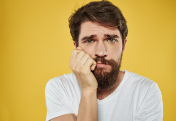Obraz premium Frightened sad man touching face with hands on yellow background cropped view