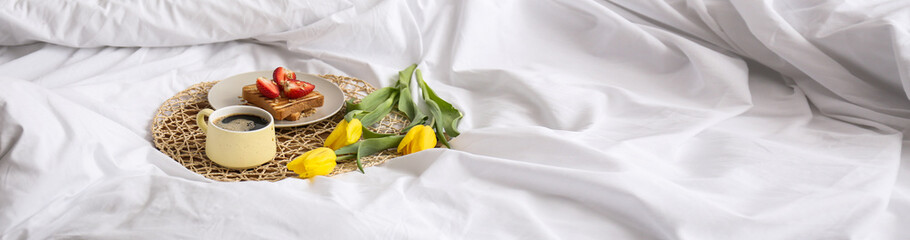 Tray with tasty breakfast on bed