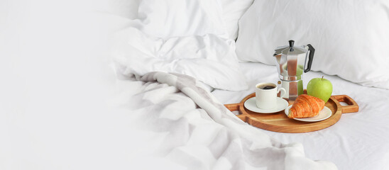 Tray with tasty breakfast on bed