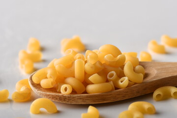 uncooked elbow macaroni on a white background.
