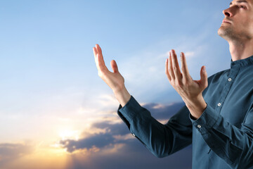 Religious man praying to God at sunrise
