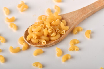 uncooked elbow macaroni on a white background.
