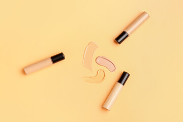 Bottles of makeup foundation and samples on color background