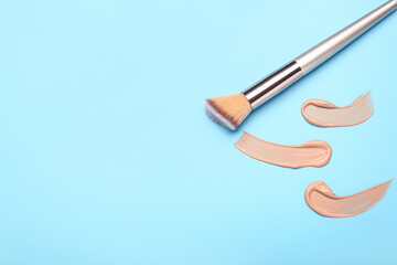Samples of makeup foundation and brush on color background
