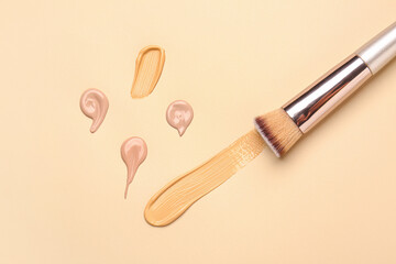 Samples of makeup foundation and brush on color background