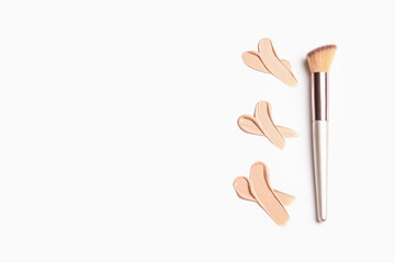 Samples of makeup foundation and brush on white background