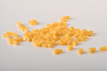 uncooked elbow macaroni on a white background.
