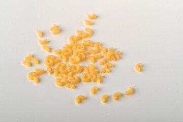 uncooked elbow macaroni on a white background.
