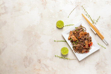 Plate with tasty soba noodles and meat on light background