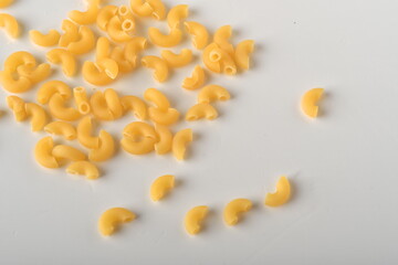 uncooked elbow macaroni on a white background.
