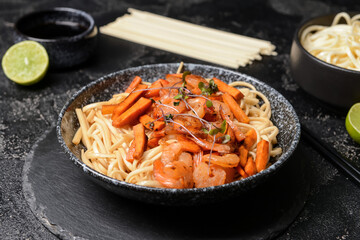 Plate with tasty noodles and shrimps on dark background