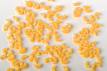 uncooked elbow macaroni on a white background.
