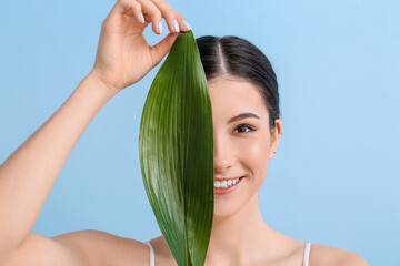 Beautiful young woman with tropical leaf on color background, closeup