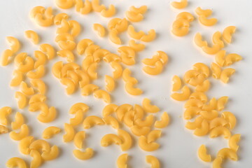 uncooked elbow macaroni on a white background.
