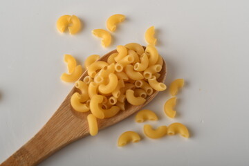 uncooked elbow macaroni on a white background.

