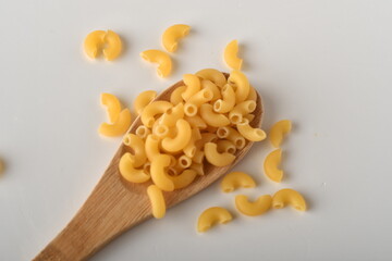 uncooked elbow macaroni on a white background.
