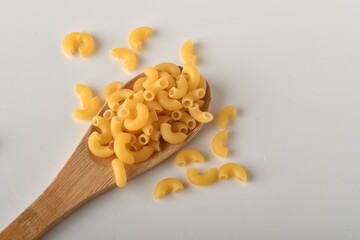 uncooked elbow macaroni on a white background.
