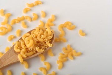 uncooked elbow macaroni on a white background.
