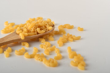 uncooked elbow macaroni on a white background.
