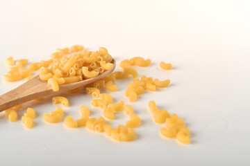 uncooked elbow macaroni on a white background.
