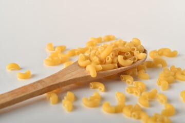 uncooked elbow macaroni on a white background.
