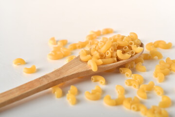 uncooked elbow macaroni on a white background.
