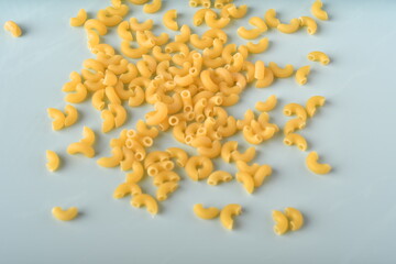 uncooked elbow macaroni on a white background.
