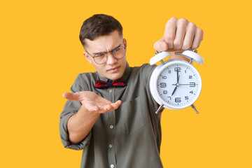 Stressed teenager with alarm clock on color background