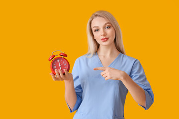 Female doctor with alarm clock on color background. Time to check your health