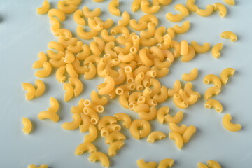 uncooked elbow macaroni on a white background.
