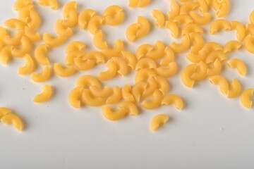 uncooked elbow macaroni on a white background.
