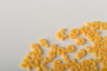 uncooked elbow macaroni on a white background.
