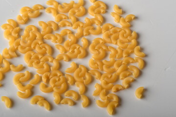 uncooked elbow macaroni on a white background.
