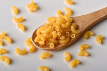 uncooked elbow macaroni on a white background.
