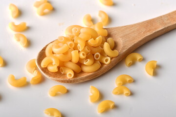 uncooked elbow macaroni on a white background.
