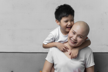 Young adult female cancer patient spending time with son at home, relaxing on the couch. Cancer and family support concept.