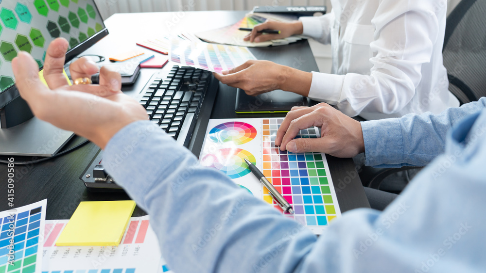 Poster graphic designer team working on web design using color swatches editing artwork using tablet and a 