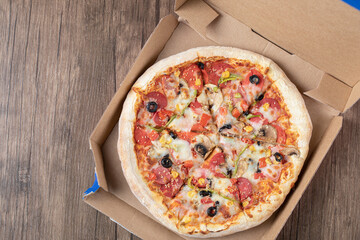Pepperoni pizza with black olives in a cardboard takeaway box