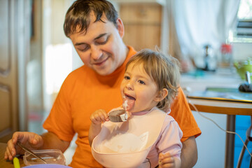 little cute toddler girl eating ice cream popsicle sitting on daddy's lap