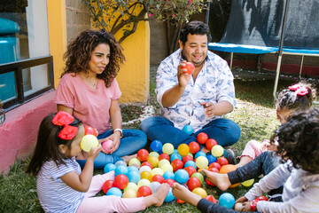 Fototapeta premium hispanic parents with children playing at backyard in home in Mexico city