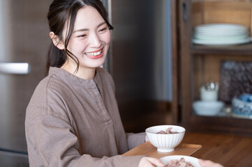 旦那さんにおかわりの配膳するかわいい日本人の新婚の奥さん