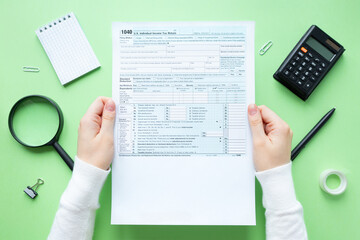A man holds a 1040 tax form in his hands. Usa taxation concept. 1040 Individual Income Tax Return 