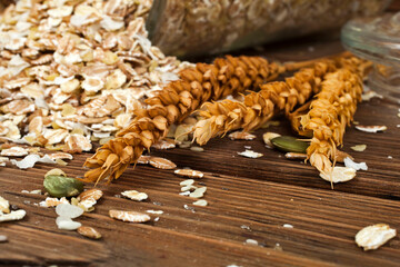Oat flakes with wheat ears on a wooden background.