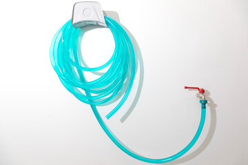 Close up of faucet connected to rubber strap hanging on wall.