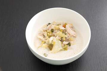 Tom Kha Gai or Thai Coconut Chicken Soup in white bowl isolated on black backdrop.