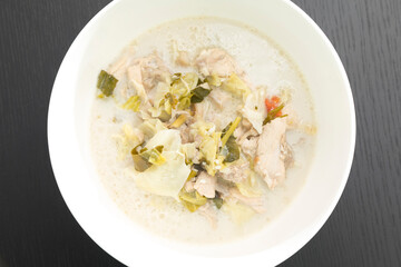 Tom Kha Gai or Thai Coconut Chicken Soup in white bowl isolated on black backdrop.