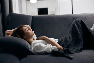 woman covered with a blanket is resting lying on the sofa in the room Comfort Cozy
